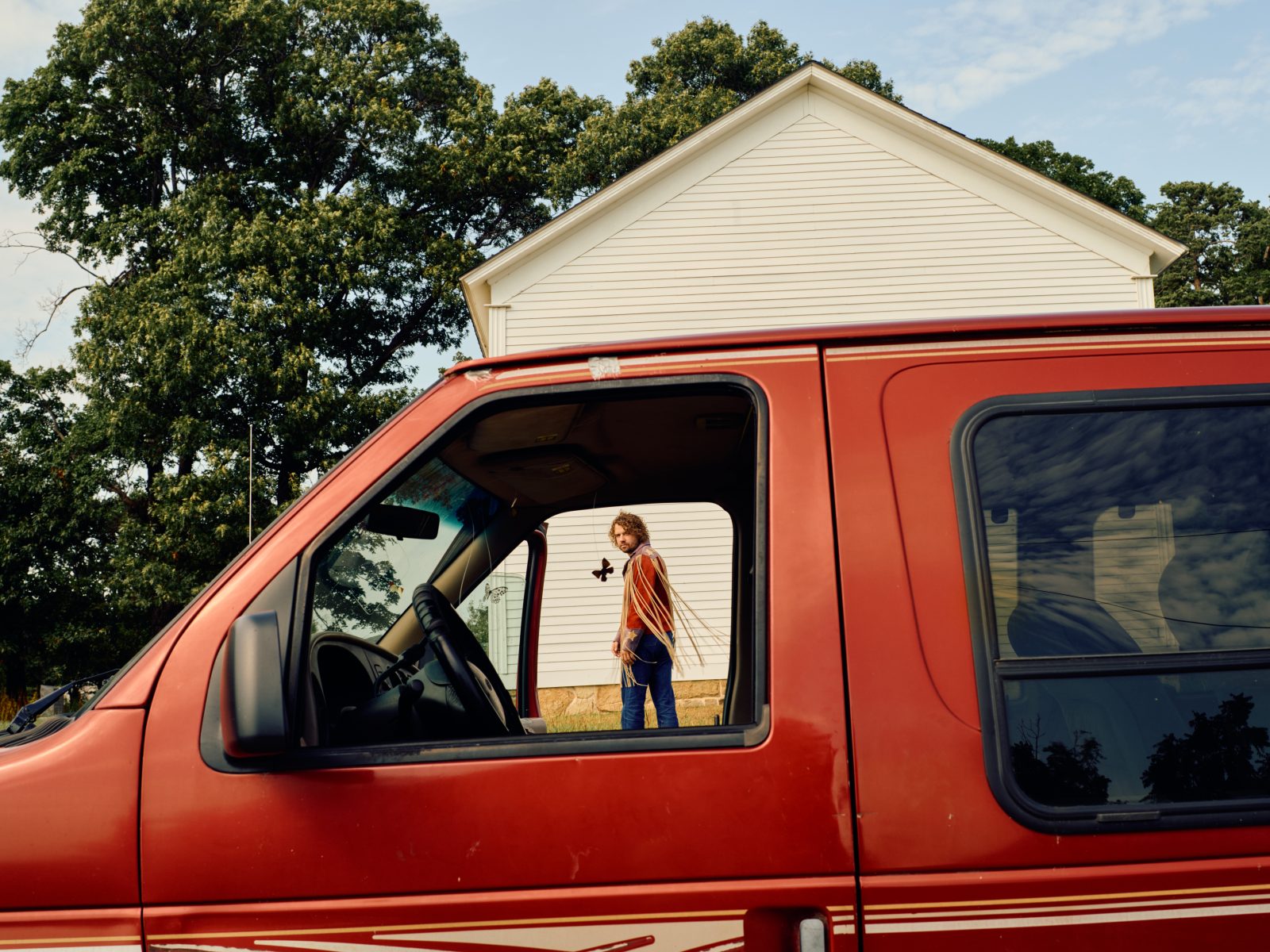 Kevin Morby stands in frame of a red van's window