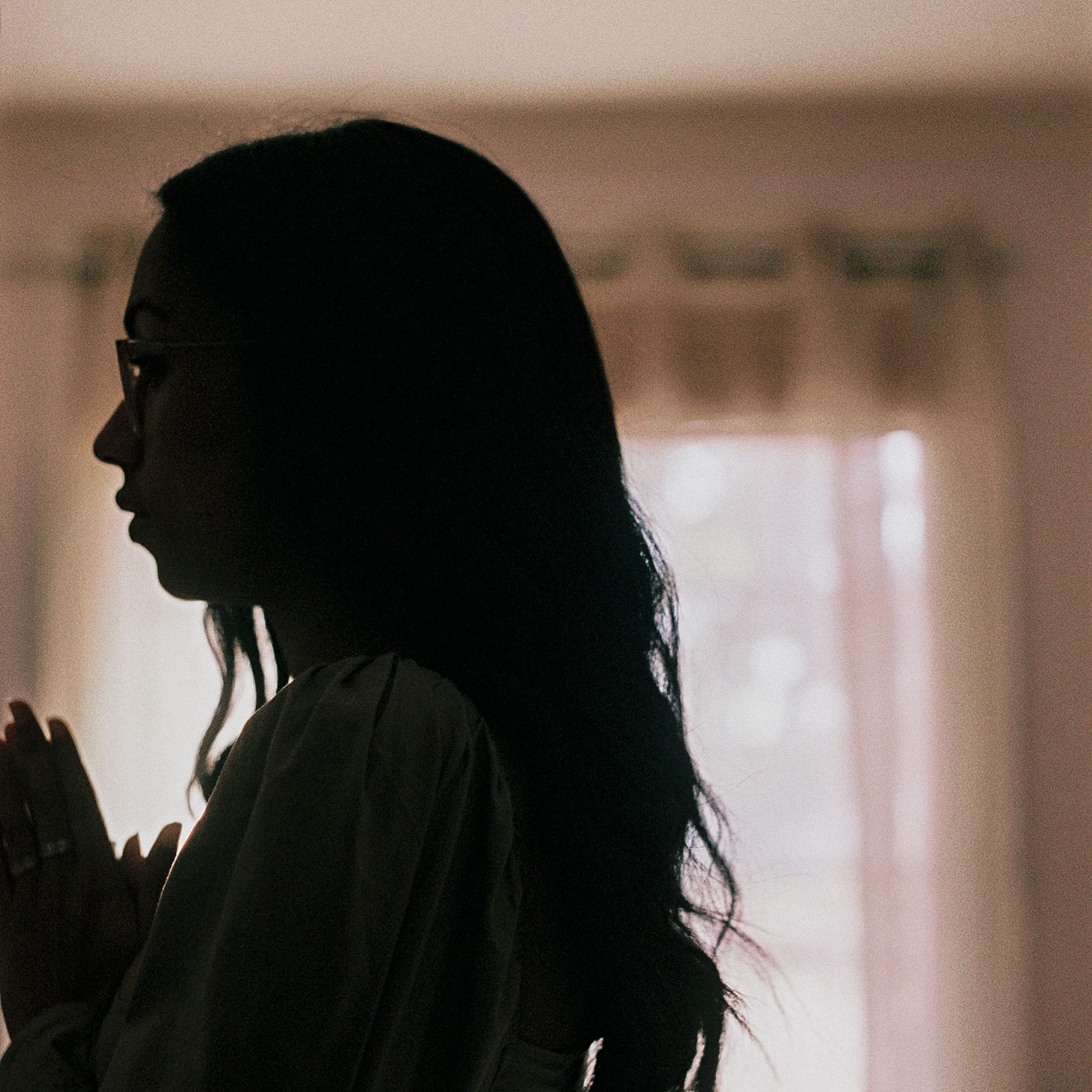 dark silhouette of Jensen in front of a pale lace curtain