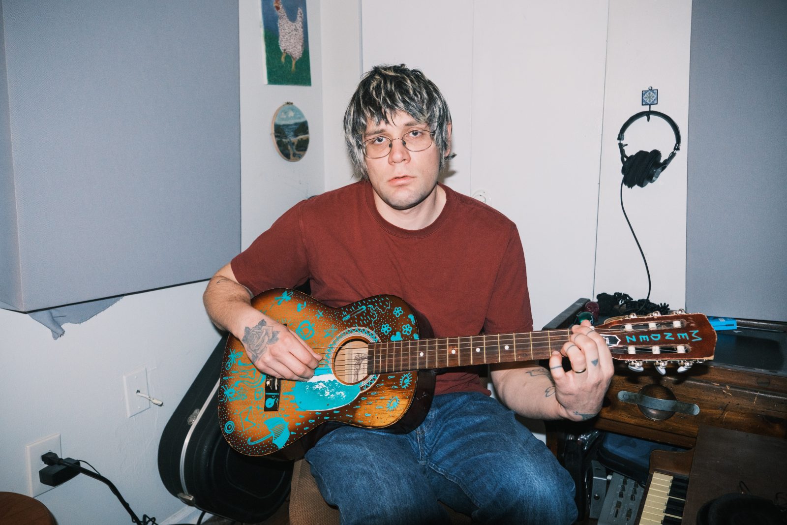 Mendez sitting a bedroom holding a guitar.